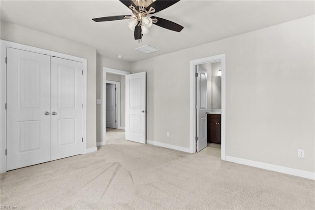 unfurnished bedroom featuring ceiling fan, light colored carpet, ensuite bathroom, and a closet