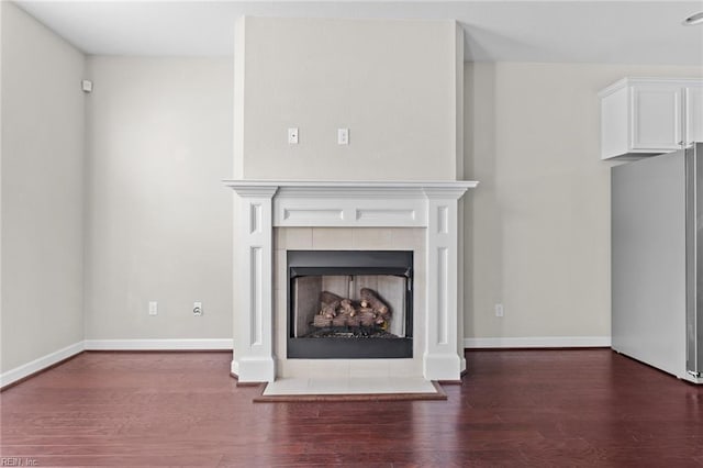 unfurnished living room featuring a tile fireplace and dark wood-type flooring