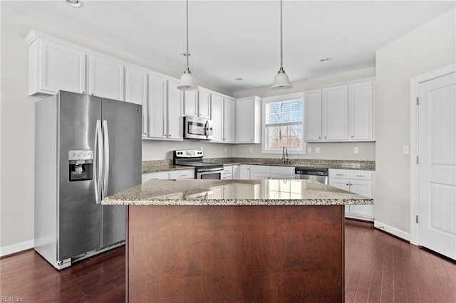 kitchen featuring appliances with stainless steel finishes, pendant lighting, a center island, and light stone counters