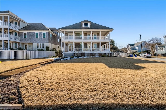 rear view of property featuring a porch, a yard, and a balcony