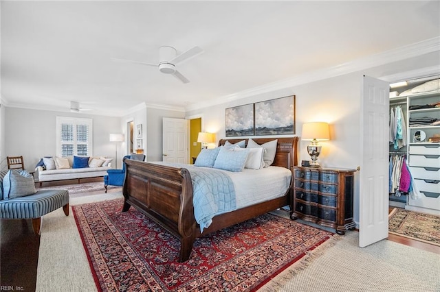 bedroom with ceiling fan, crown molding, and a closet