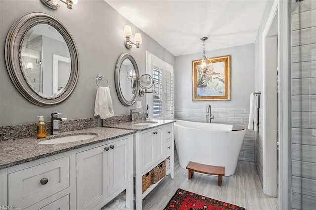 bathroom with tile walls, a tub to relax in, and vanity