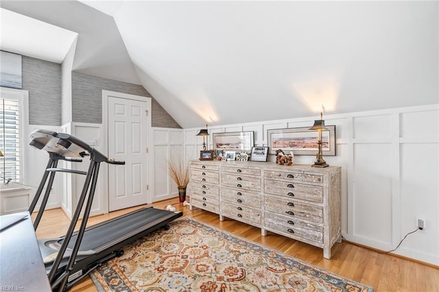 workout room featuring light wood-type flooring and vaulted ceiling