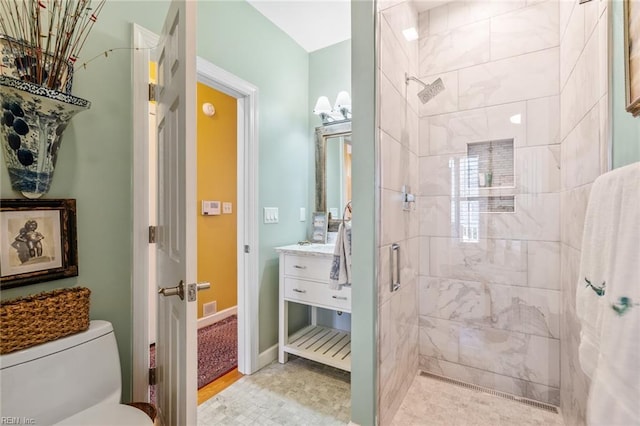 bathroom with toilet, tiled shower, and vanity