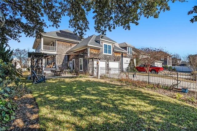 back of house featuring a lawn, solar panels, a balcony, and a garage