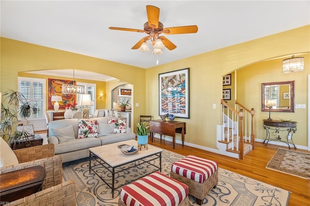 living room with ceiling fan with notable chandelier and hardwood / wood-style flooring