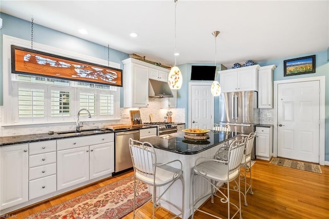 kitchen featuring a center island, decorative light fixtures, white cabinets, appliances with stainless steel finishes, and sink