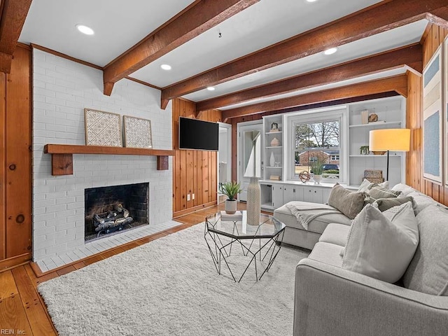 living room with light hardwood / wood-style flooring, a brick fireplace, and wooden walls