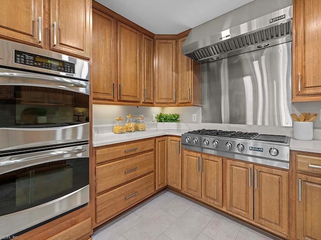 kitchen featuring light tile patterned flooring, ventilation hood, and appliances with stainless steel finishes