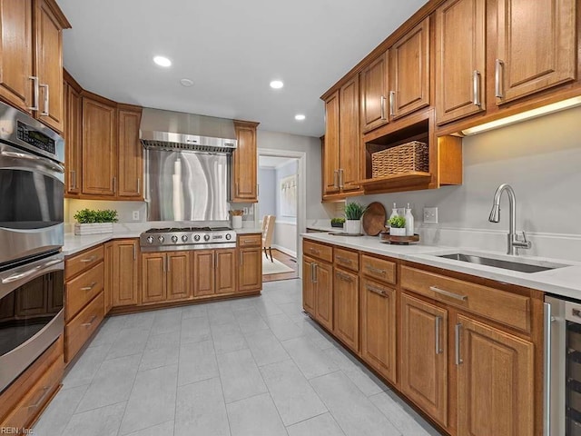 kitchen with stainless steel appliances, beverage cooler, sink, and wall chimney range hood