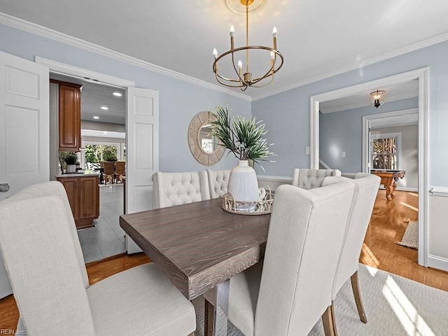 dining area featuring a chandelier, light wood-type flooring, and crown molding