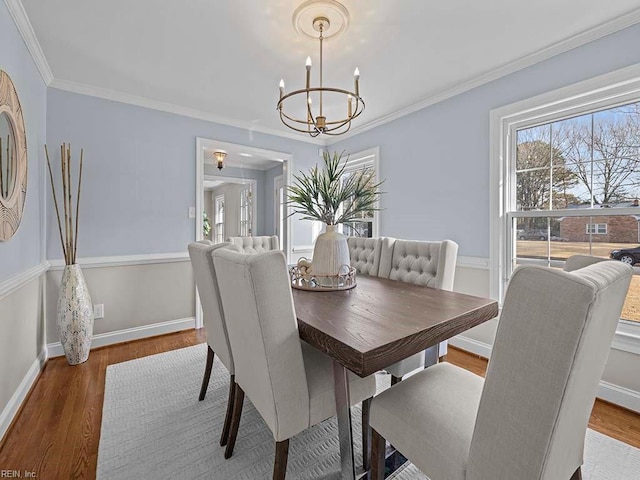 dining area with hardwood / wood-style flooring, ornamental molding, and a chandelier