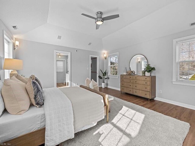 bedroom with multiple windows, connected bathroom, ceiling fan, and dark hardwood / wood-style floors