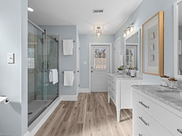 bathroom featuring an enclosed shower, vanity, and wood-type flooring