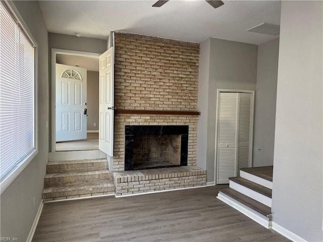 unfurnished living room featuring dark hardwood / wood-style floors, ceiling fan, and a fireplace