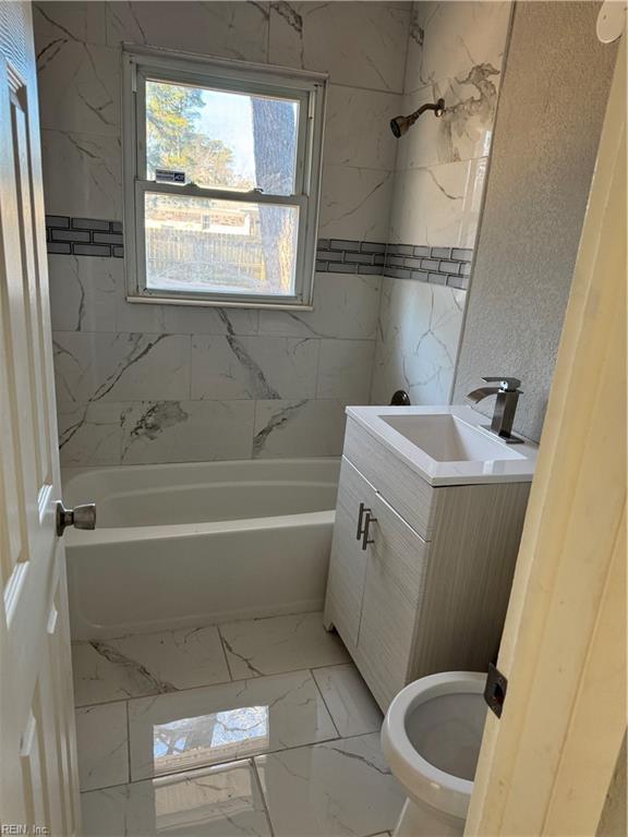 full bathroom featuring toilet, vanity, and tiled shower / bath