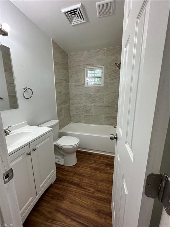 full bathroom featuring hardwood / wood-style floors, vanity, tiled shower / bath combo, and toilet