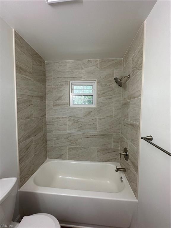 bathroom with toilet and tiled shower / bath