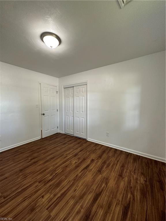 unfurnished bedroom featuring a closet and dark hardwood / wood-style floors