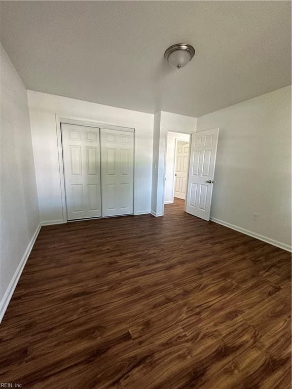 unfurnished bedroom with a closet and dark wood-type flooring