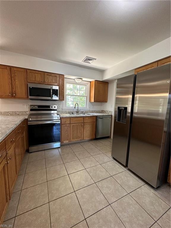 kitchen with sink, light tile patterned floors, and stainless steel appliances