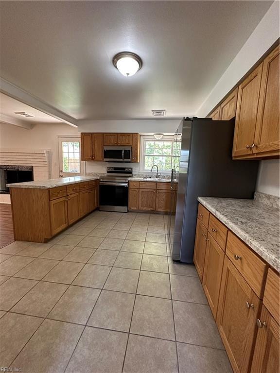 kitchen featuring sink, light stone counters, kitchen peninsula, light tile patterned flooring, and appliances with stainless steel finishes