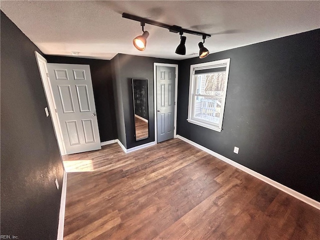 unfurnished bedroom featuring hardwood / wood-style floors, rail lighting, and a textured ceiling