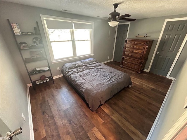 bedroom with ceiling fan, dark hardwood / wood-style floors, and a textured ceiling