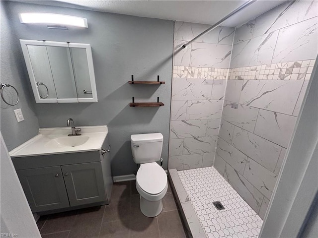 bathroom with tile patterned flooring, toilet, vanity, and tiled shower