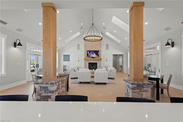 dining space with ornate columns, a brick fireplace, high vaulted ceiling, light parquet floors, and a chandelier