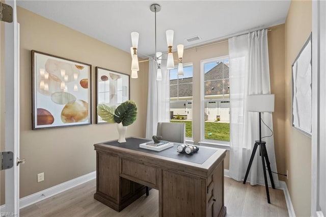 office space featuring light wood-type flooring and a notable chandelier