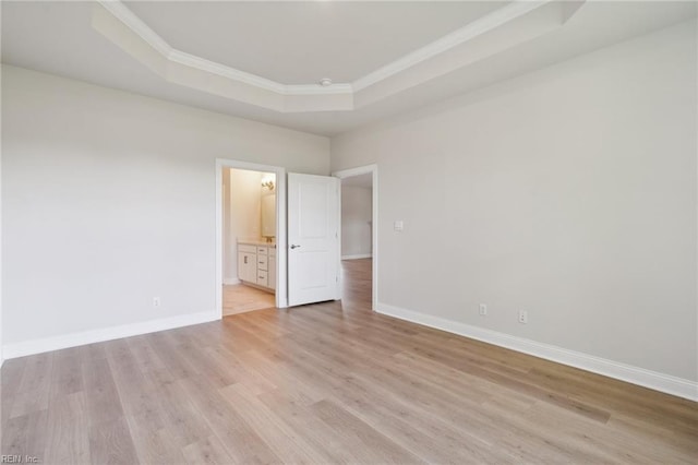 spare room featuring a tray ceiling, crown molding, and light hardwood / wood-style floors