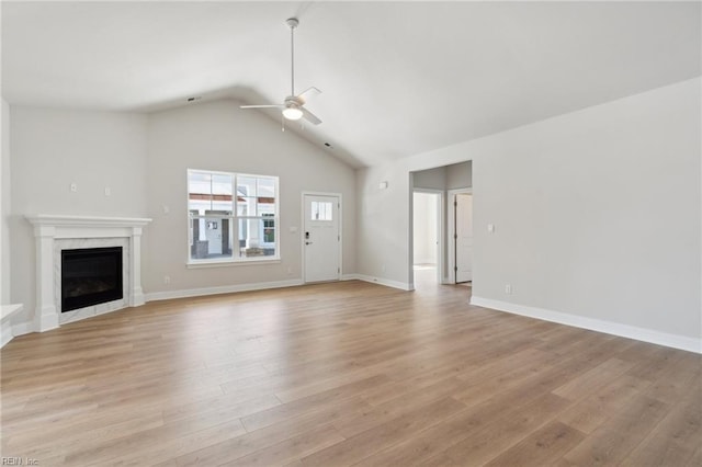 unfurnished living room with a premium fireplace, ceiling fan, light hardwood / wood-style floors, and vaulted ceiling