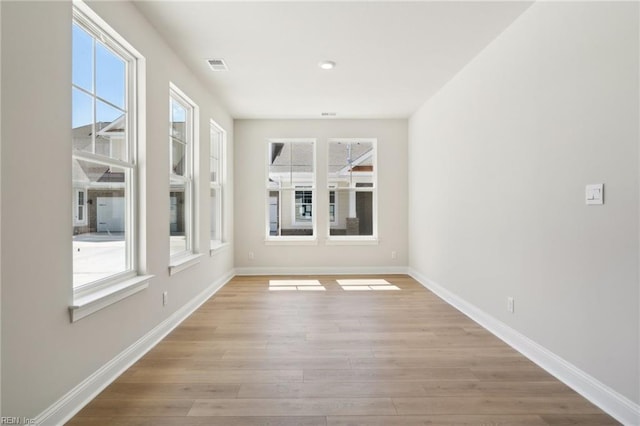 unfurnished room with a healthy amount of sunlight and light hardwood / wood-style flooring