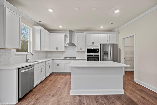 kitchen with wall chimney exhaust hood, stainless steel appliances, sink, white cabinets, and a center island