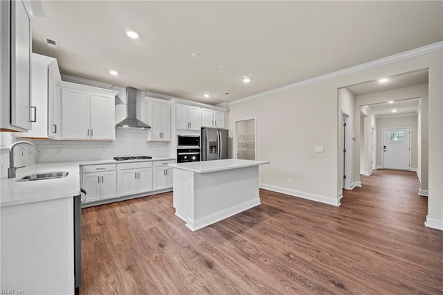 kitchen with stainless steel fridge, wall chimney exhaust hood, sink, a center island, and white cabinetry