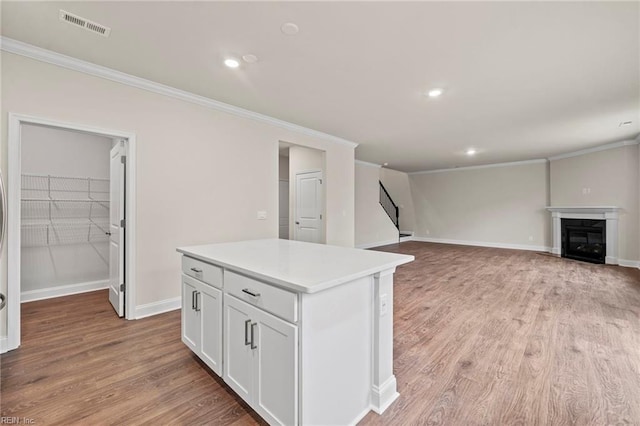 kitchen with a center island, light wood-type flooring, white cabinetry, and crown molding