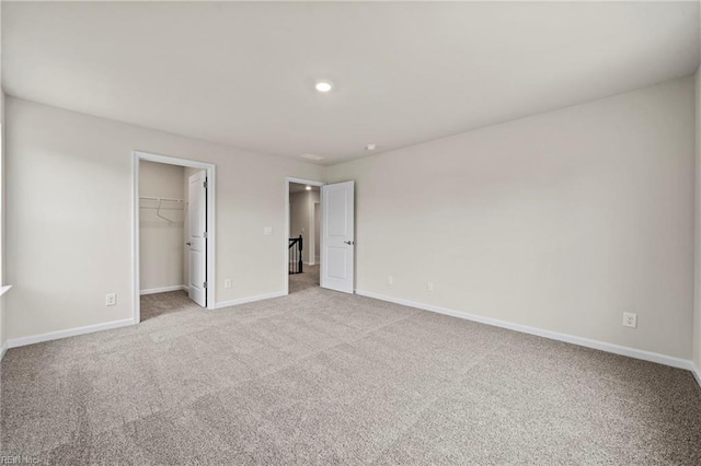 unfurnished bedroom featuring a walk in closet, light carpet, and a closet