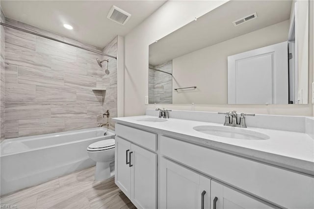 full bathroom with vanity, tiled shower / bath combo, and toilet