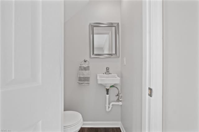 bathroom featuring wood-type flooring, vaulted ceiling, and toilet