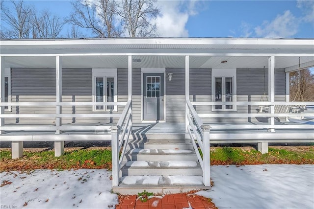 snow covered property entrance featuring a porch