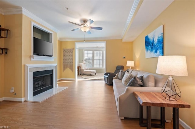 living room with light wood-type flooring, ceiling fan, and crown molding