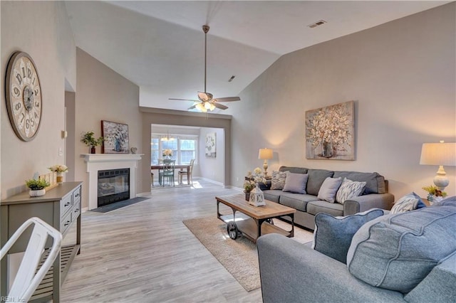 living room with ceiling fan, light hardwood / wood-style floors, and lofted ceiling