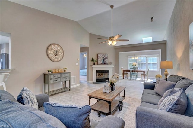 living room featuring ceiling fan, vaulted ceiling, and light wood-type flooring