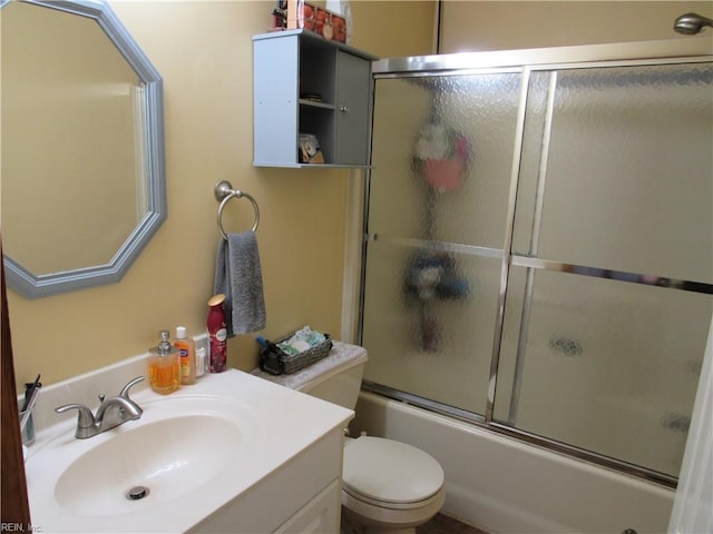 full bathroom featuring combined bath / shower with glass door, toilet, and vanity