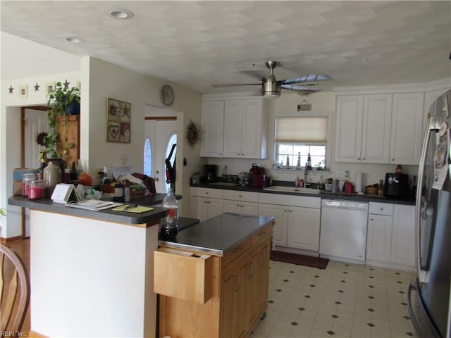 kitchen featuring white dishwasher, a kitchen island, ceiling fan, white cabinets, and stainless steel refrigerator