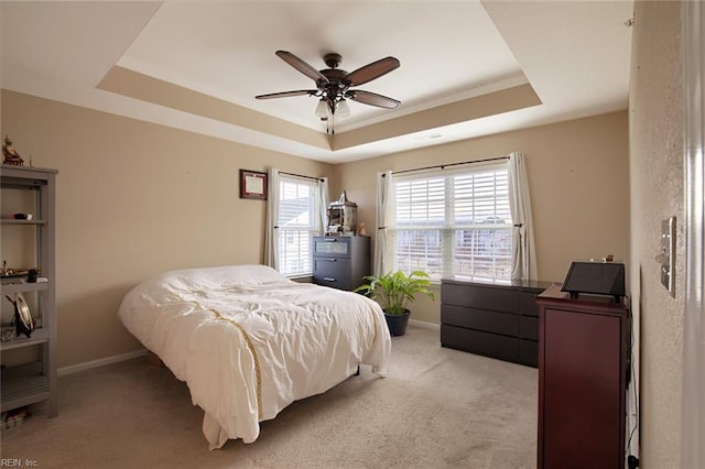 carpeted bedroom with a tray ceiling and ceiling fan