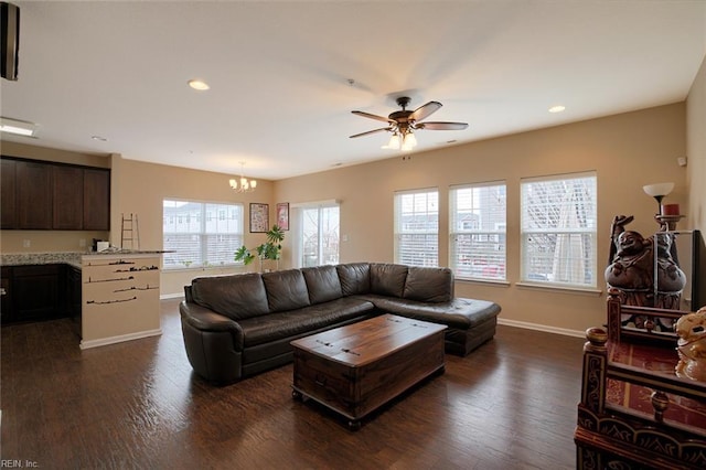 living room featuring ceiling fan with notable chandelier and dark wood-type flooring