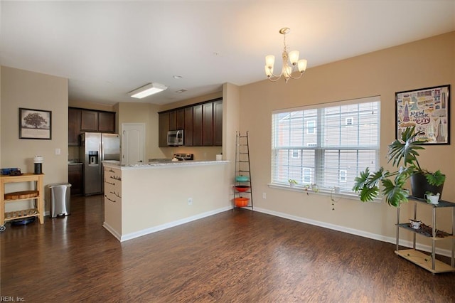 kitchen featuring dark wood-type flooring, an inviting chandelier, light stone counters, dark brown cabinets, and appliances with stainless steel finishes