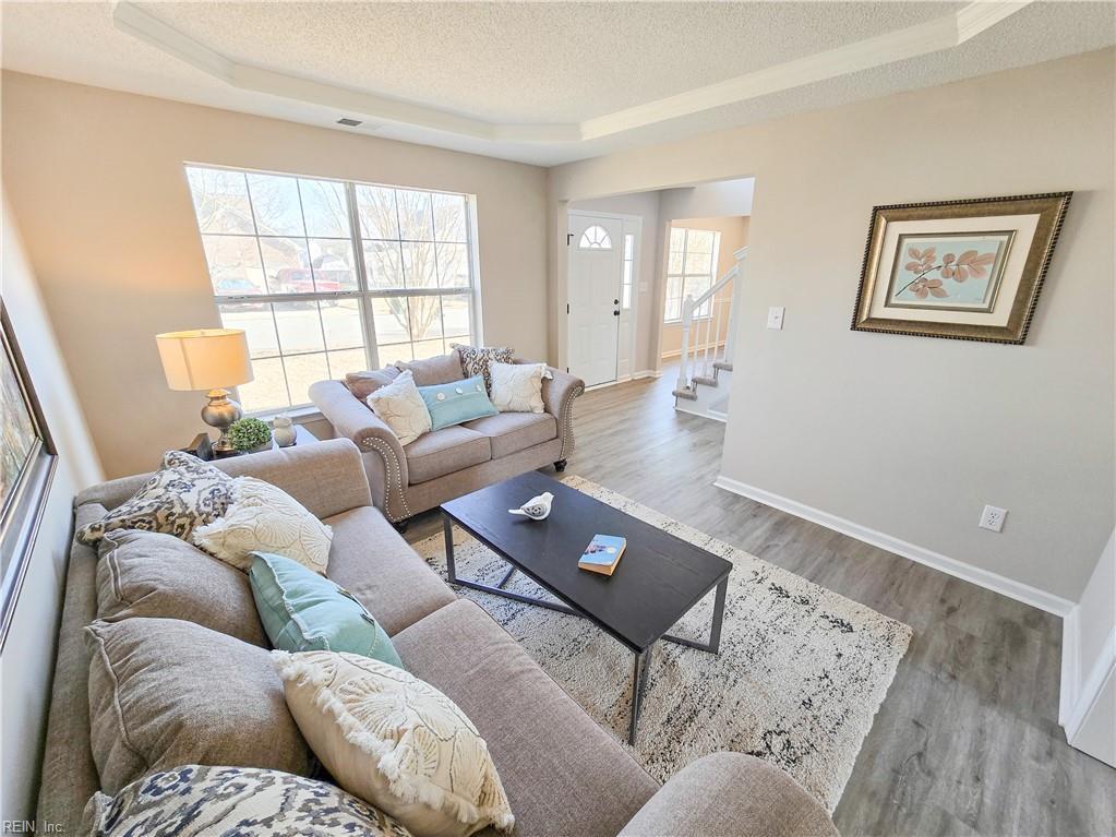 living room featuring a textured ceiling, wood-type flooring, and a raised ceiling